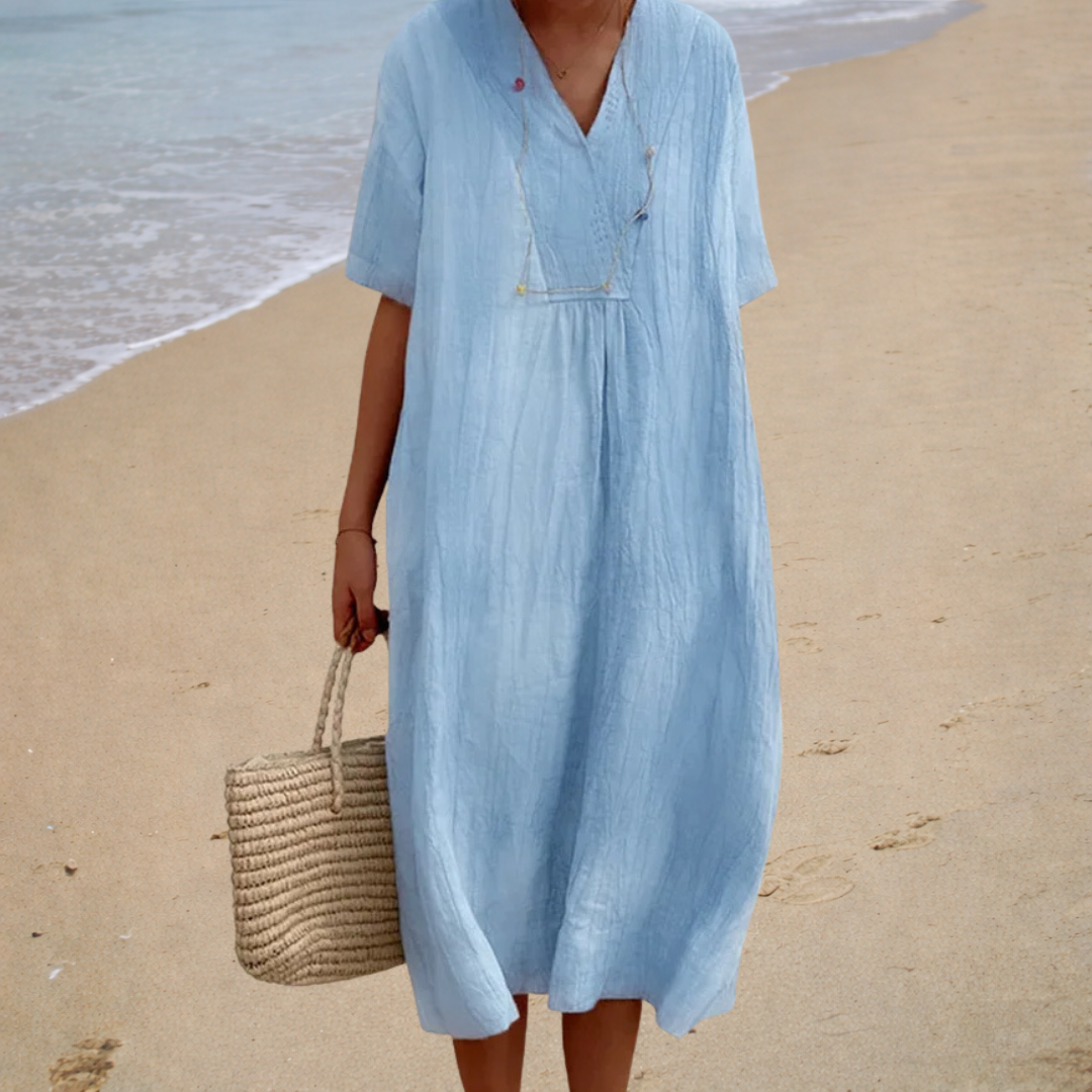 A woman wearing a light, solid-coloured summer dress with a relaxed, flowing shape.