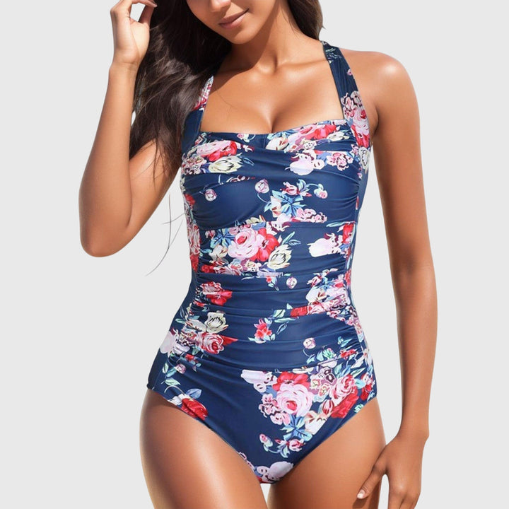 A woman poolside in a patterned one-piece swimsuit, relaxed and confident in the sunshine.