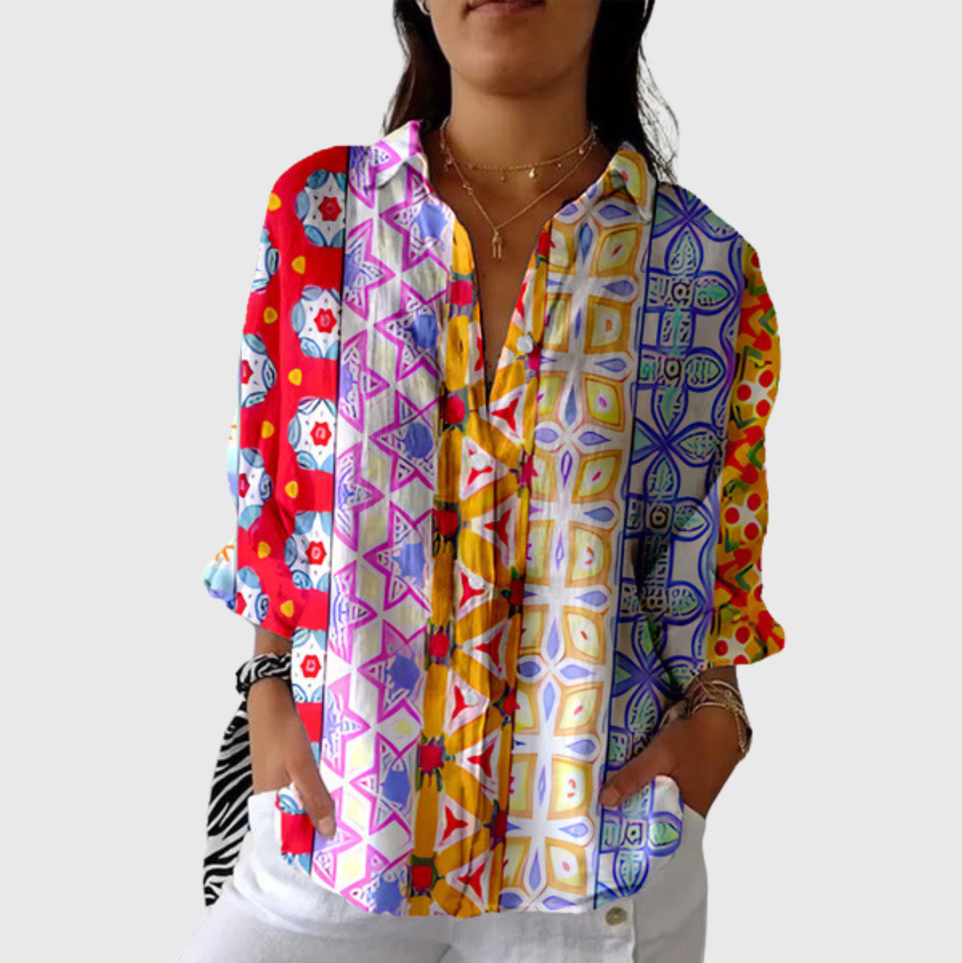 A woman wearing a loose colourful printed blouse with adjustable sleeves, styled with jeans for an effortless day out.
