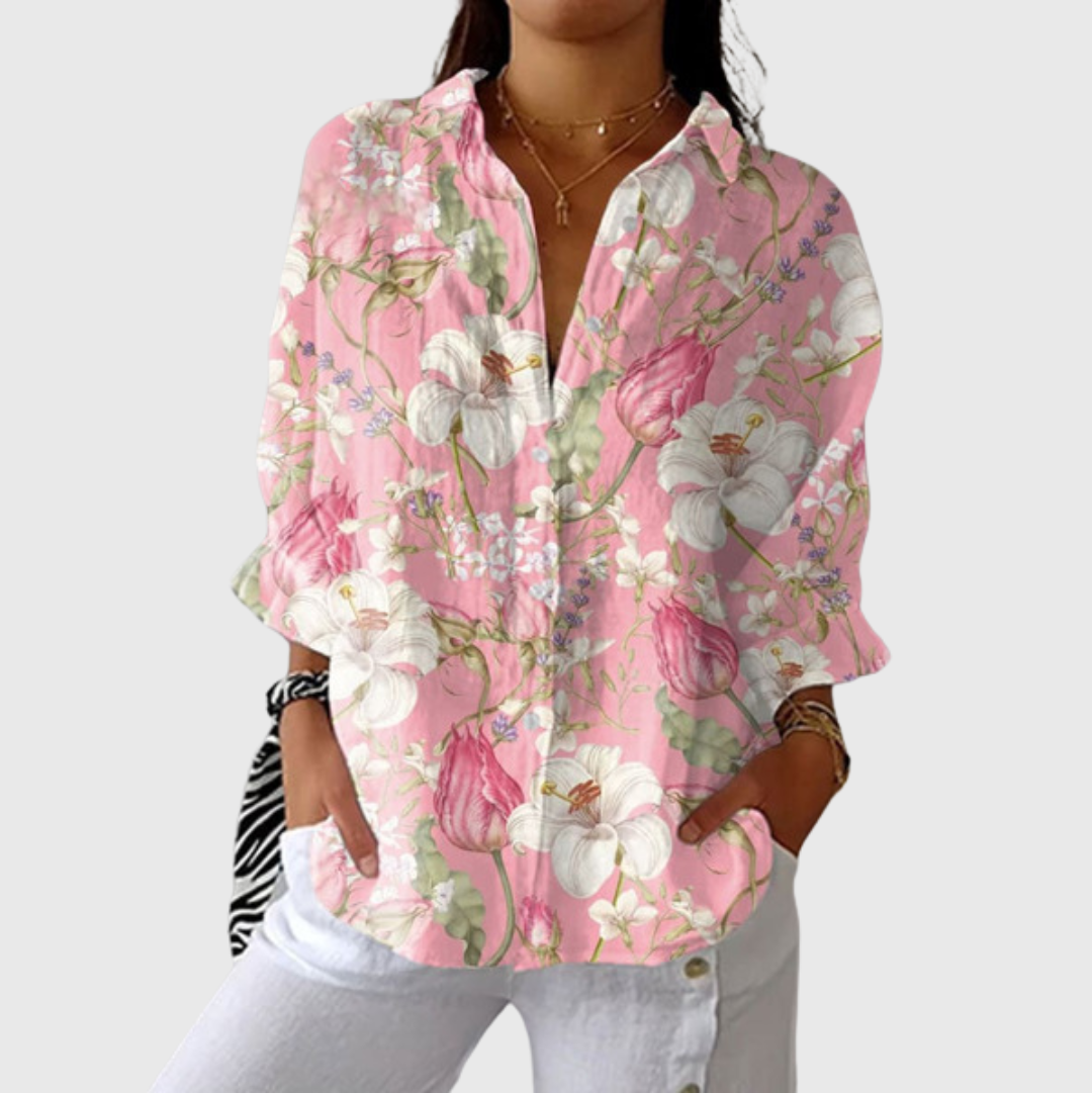 A woman wearing a loose colourful printed blouse with adjustable sleeves, styled with pants for an easy day out.