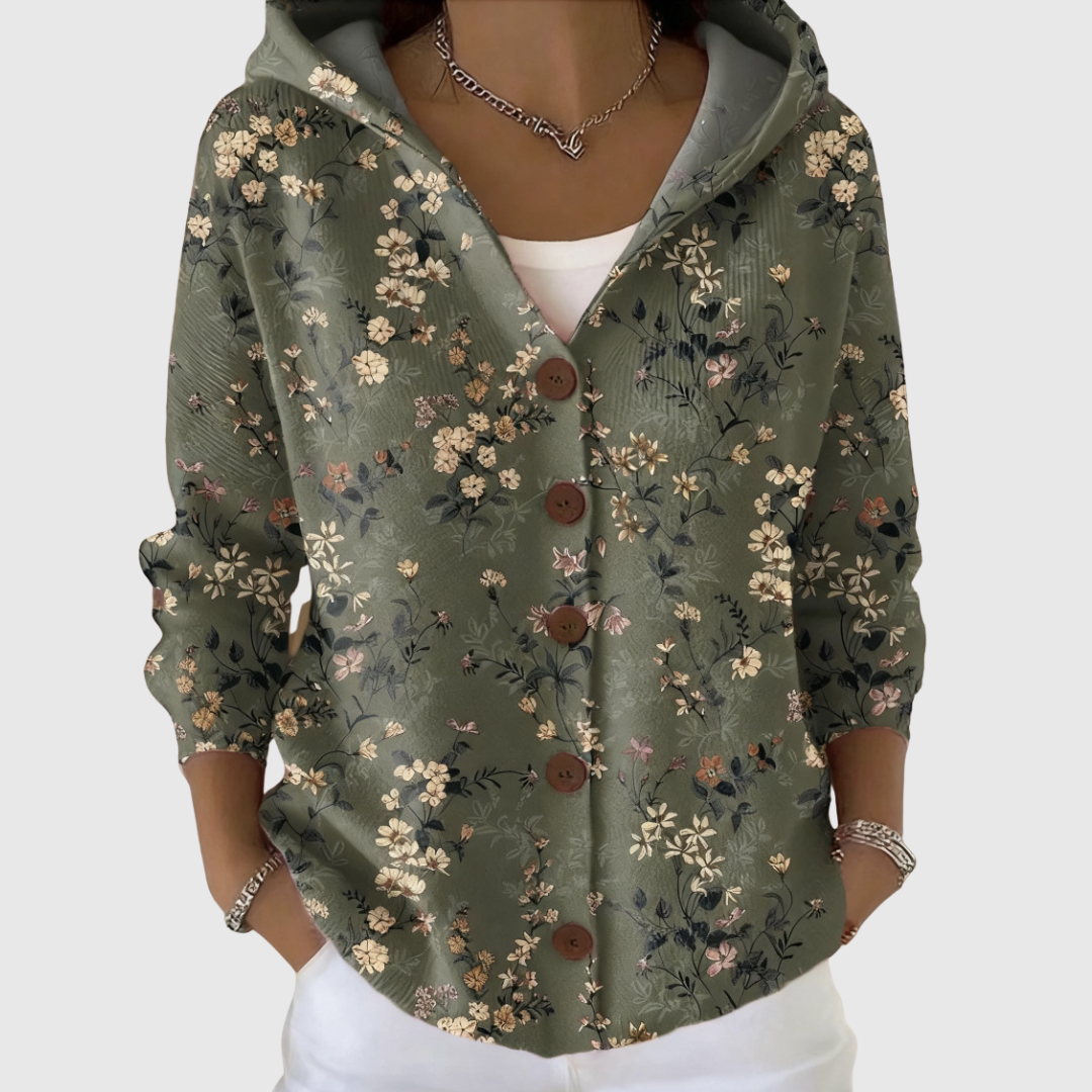 A woman wearing a sage green floral print hooded button cardigan over a white top.