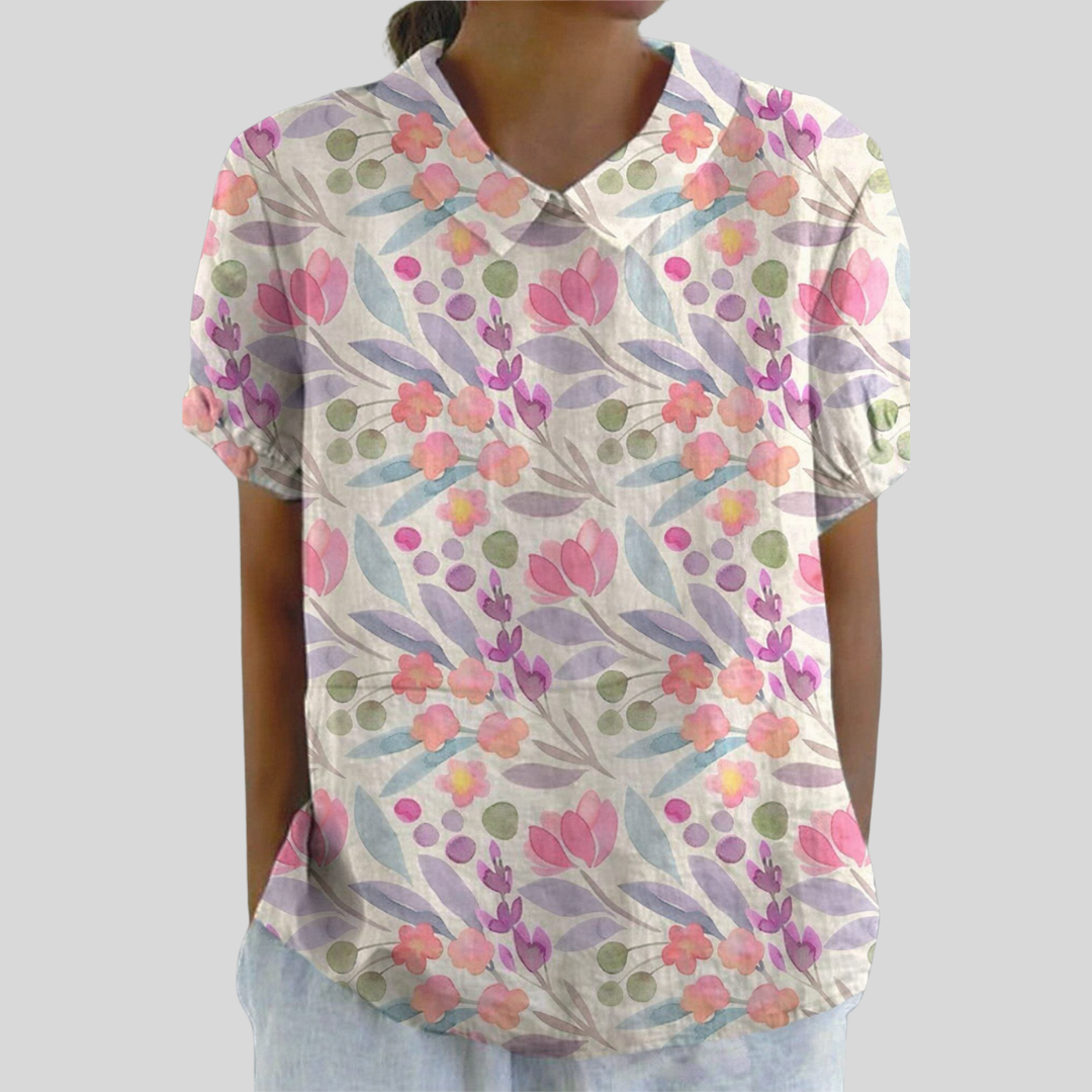A woman wearing a flowing floral top with a polo collar, looking feminine and relaxed.