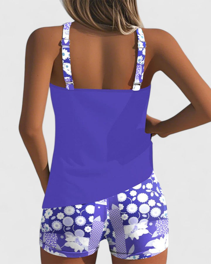 A woman wearing a blue tankini set with a loose tank top and matching floral-print shorts.