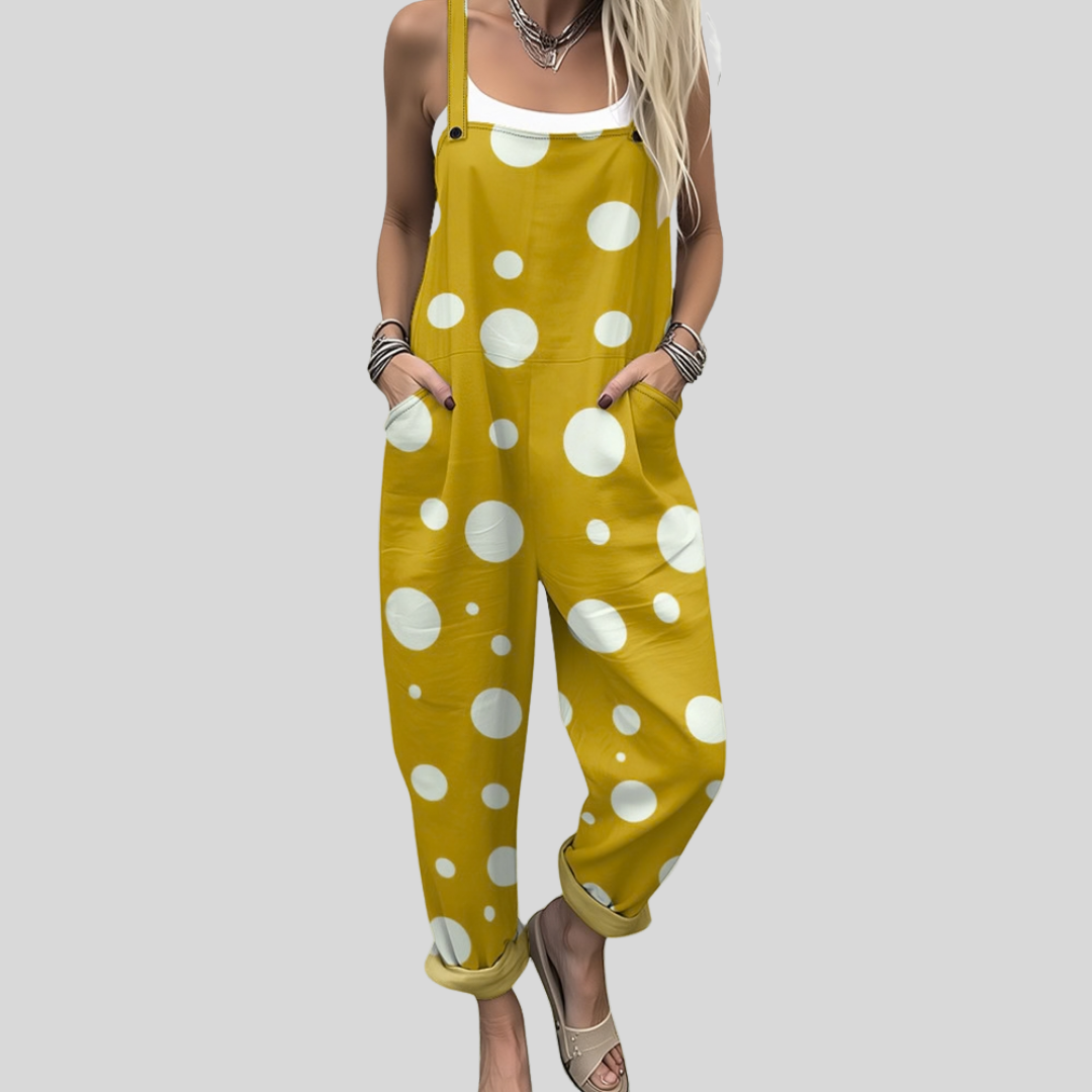 A woman wearing warm mustard yellow overalls covered in white polka dots, with adjustable straps.