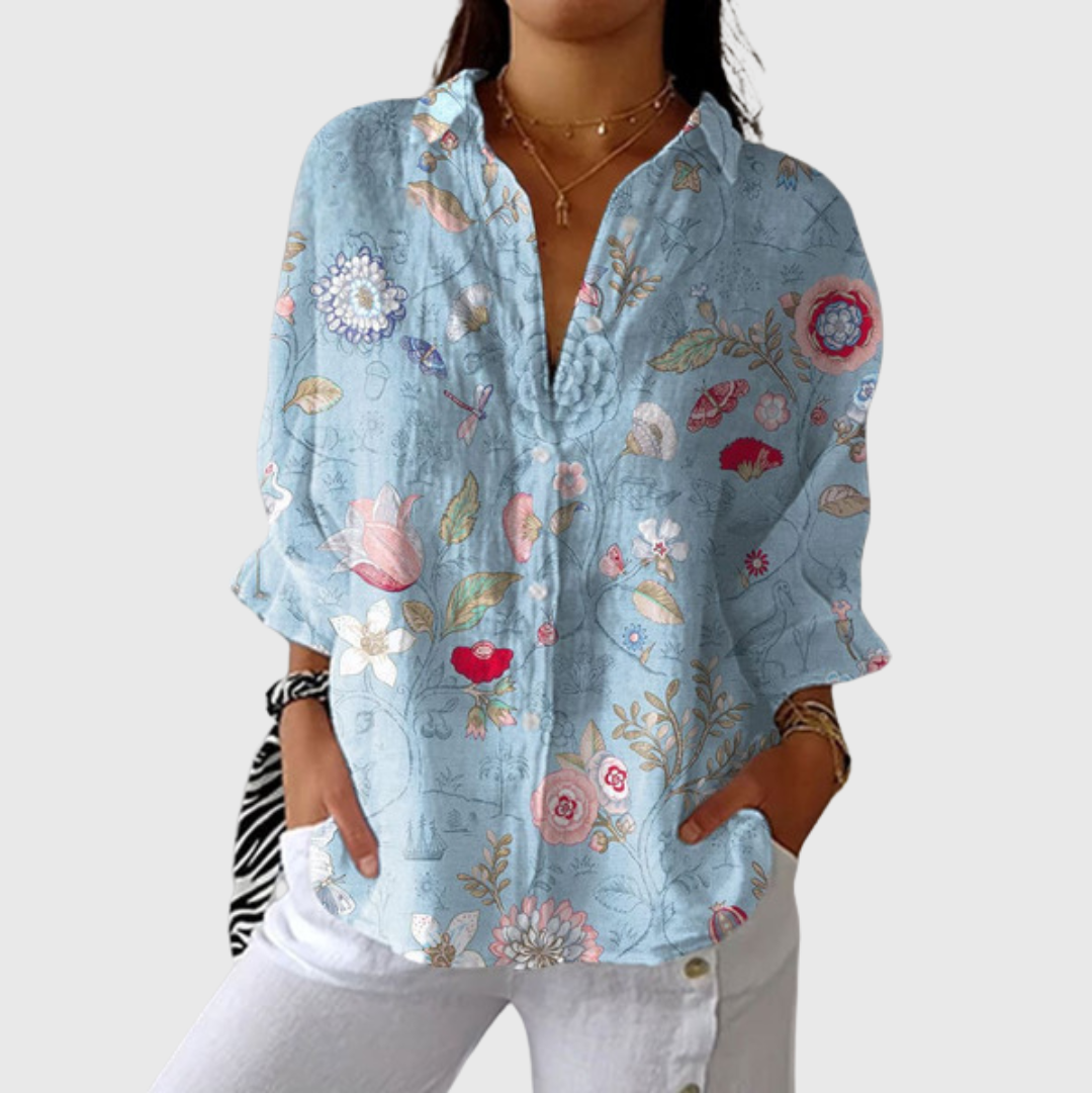 A woman wearing a bright, colourful printed blouse with a relaxed, flowing cut, looking cheerful and at ease.