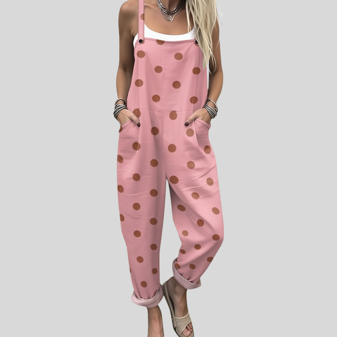 A woman wearing soft pink overalls with terracotta polka dots and adjustable straps.