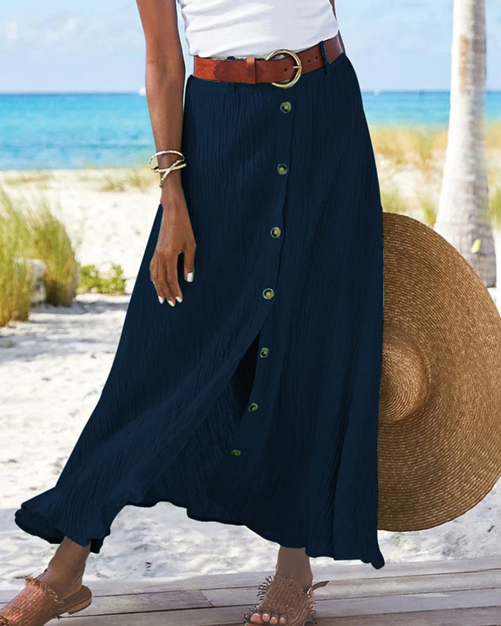 Woman wearing a flowing high-waisted button skirt with a tucked-in top, walking outdoors.