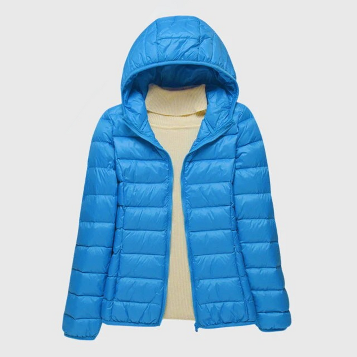 A woman wearing a lightweight padded jacket with a hood, outdoors on a cool day