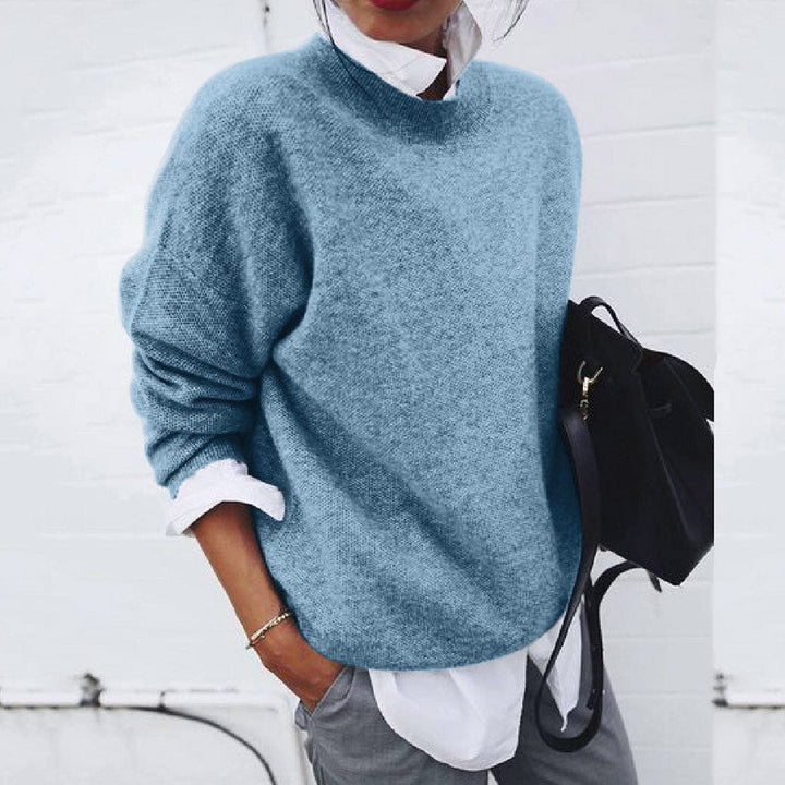 A woman wearing a soft mustard round-neck sweater with an elegant modern shape, relaxed and warm.