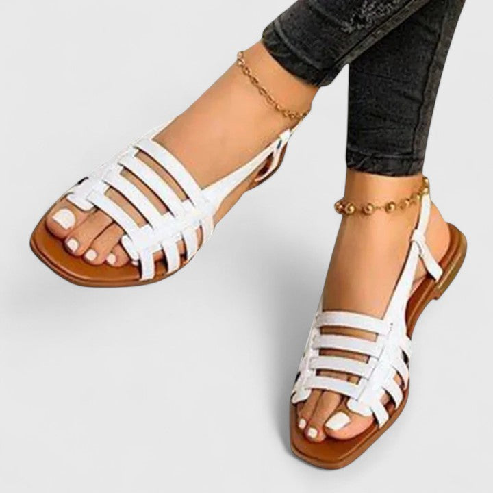 A woman wearing gold refined comfort sandals with a broad, cushioned footbed.