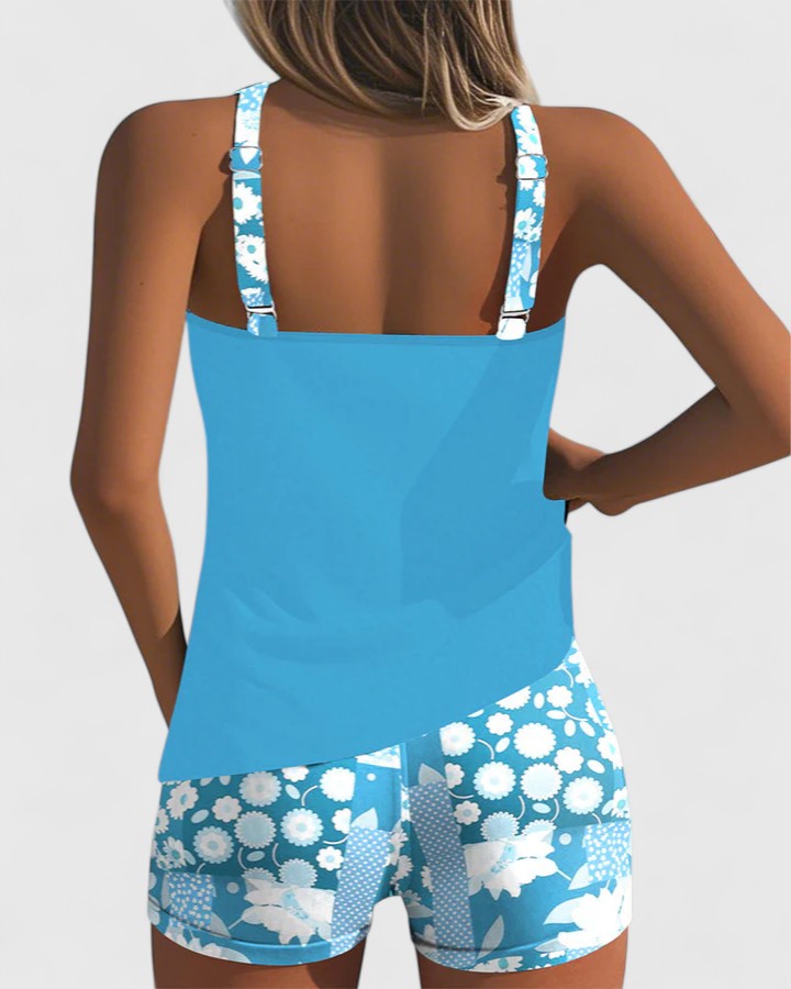 A woman wearing a blue tankini set with a loose tank top and matching floral-print shorts.