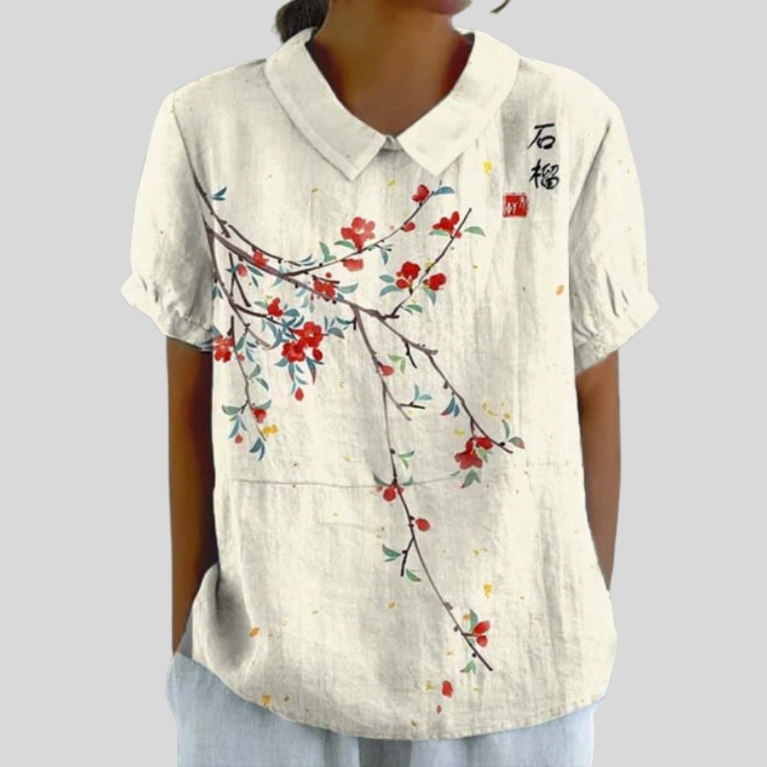 A woman wearing a flowing floral top with a neat polo collar, styled for an easy everyday look.