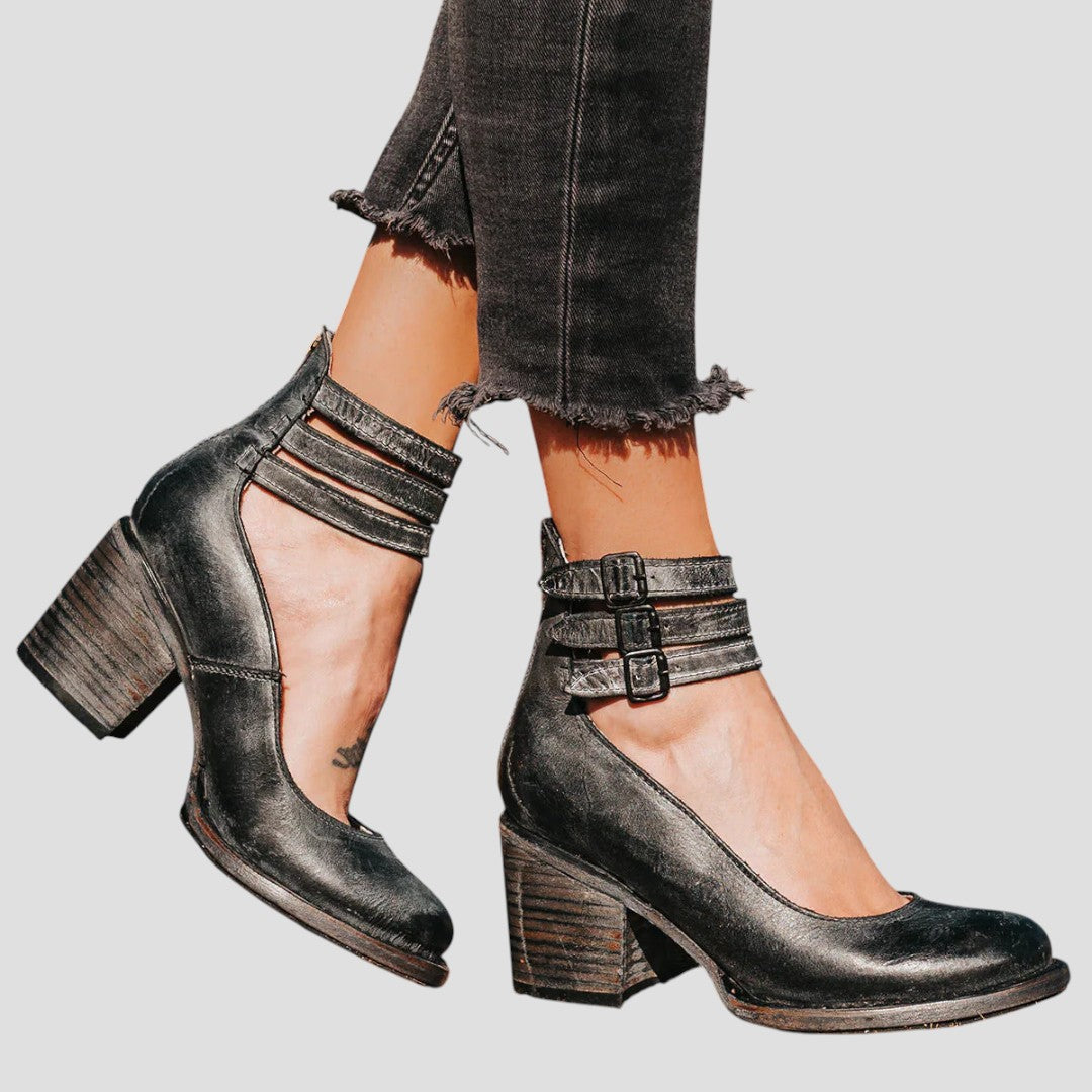 A woman wearing cognac block-heel pumps with triple ankle straps and a rounded toe.
