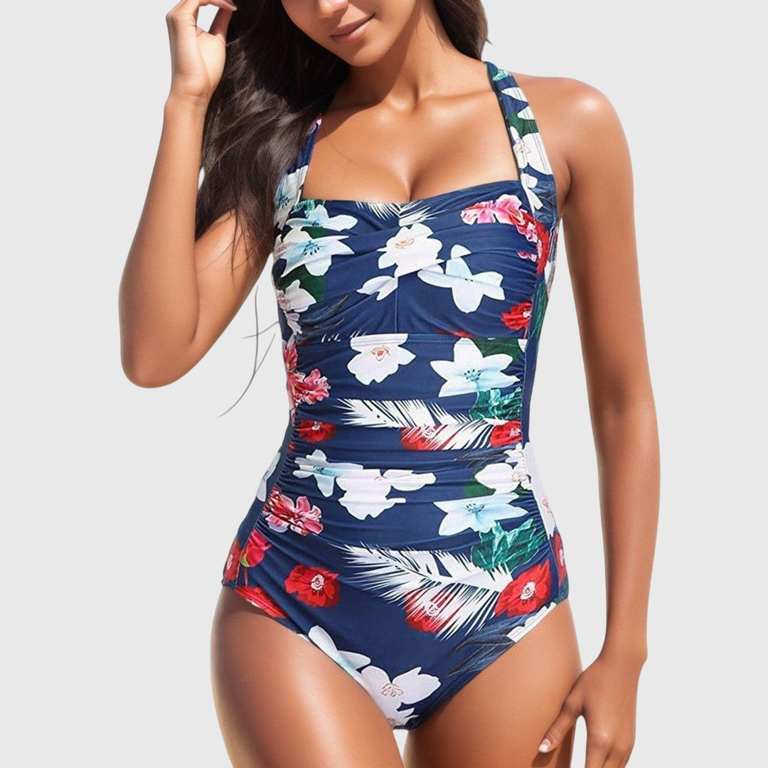 A woman poolside in a patterned one-piece swimsuit, relaxed and confident in the sunshine.