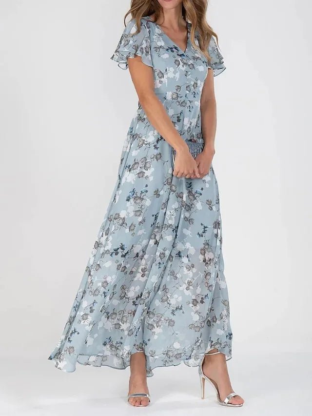 Woman wearing a long flowing wrap-effect maxi dress with a subtle floral print and floaty sleeves.