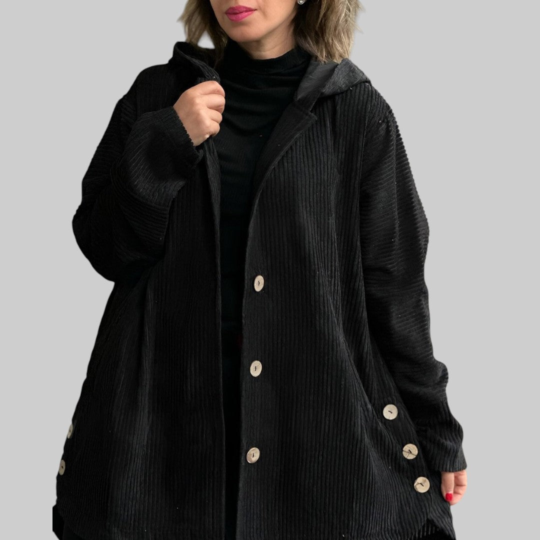 A woman wearing a hooded textured jacket outdoors in fall