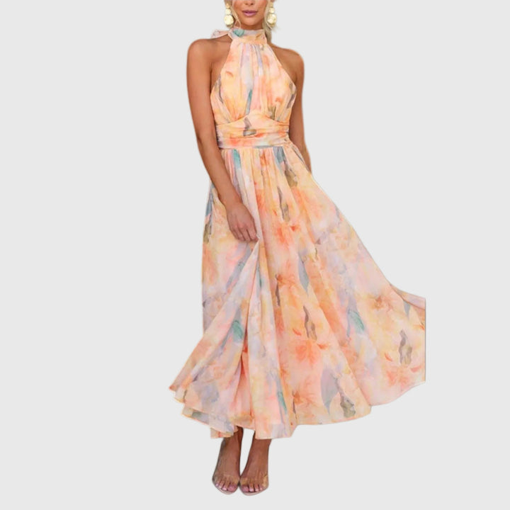 Woman wearing the Carol halterneck maxi dress in warm watercolour tones at an outdoor celebration.