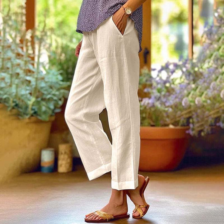 Woman wearing relaxed straight-leg pants with a soft top, standing in soft daylight.