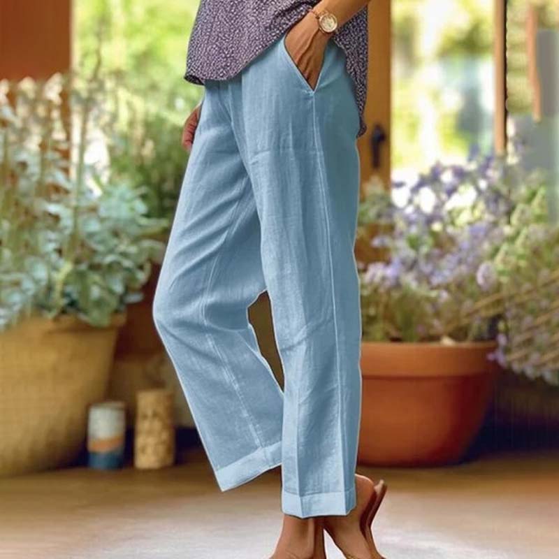 Woman wearing relaxed straight-leg pants with a soft top, standing in soft daylight.