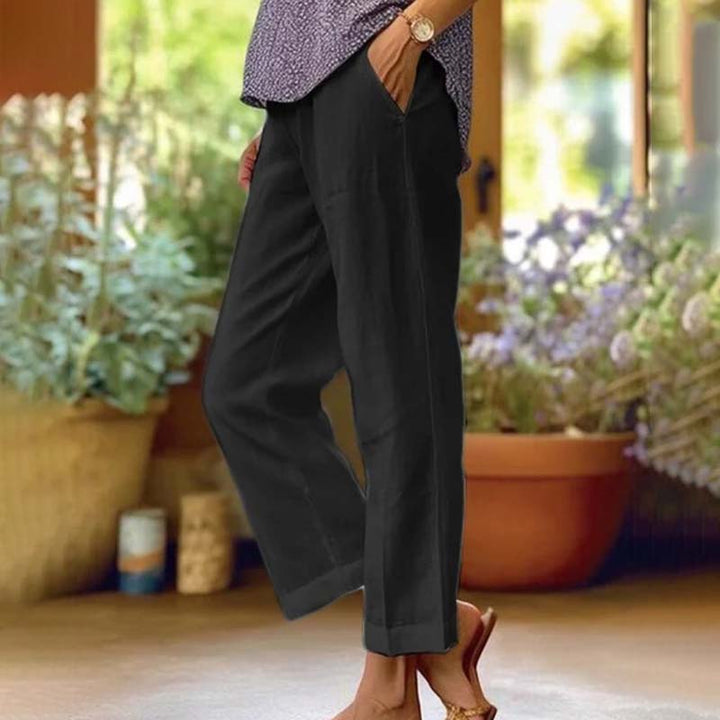 Woman wearing relaxed straight-leg pants with a soft top, standing in soft daylight.