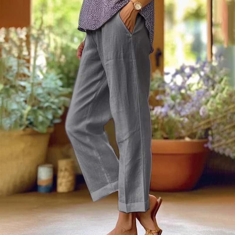 Woman wearing relaxed straight-leg pants with a soft top, standing in soft daylight.