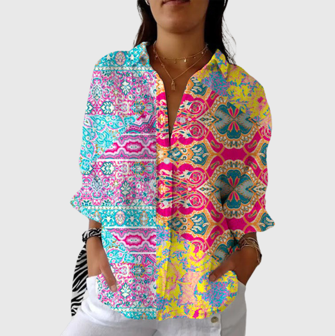 A woman wearing a relaxed colourful printed blouse with adjustable sleeves, styled with pants for a cheerful day out.