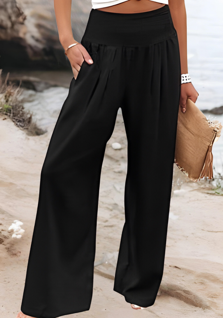 A woman walking by the sea in wide-leg beach pants with a relaxed, breezy summer look.