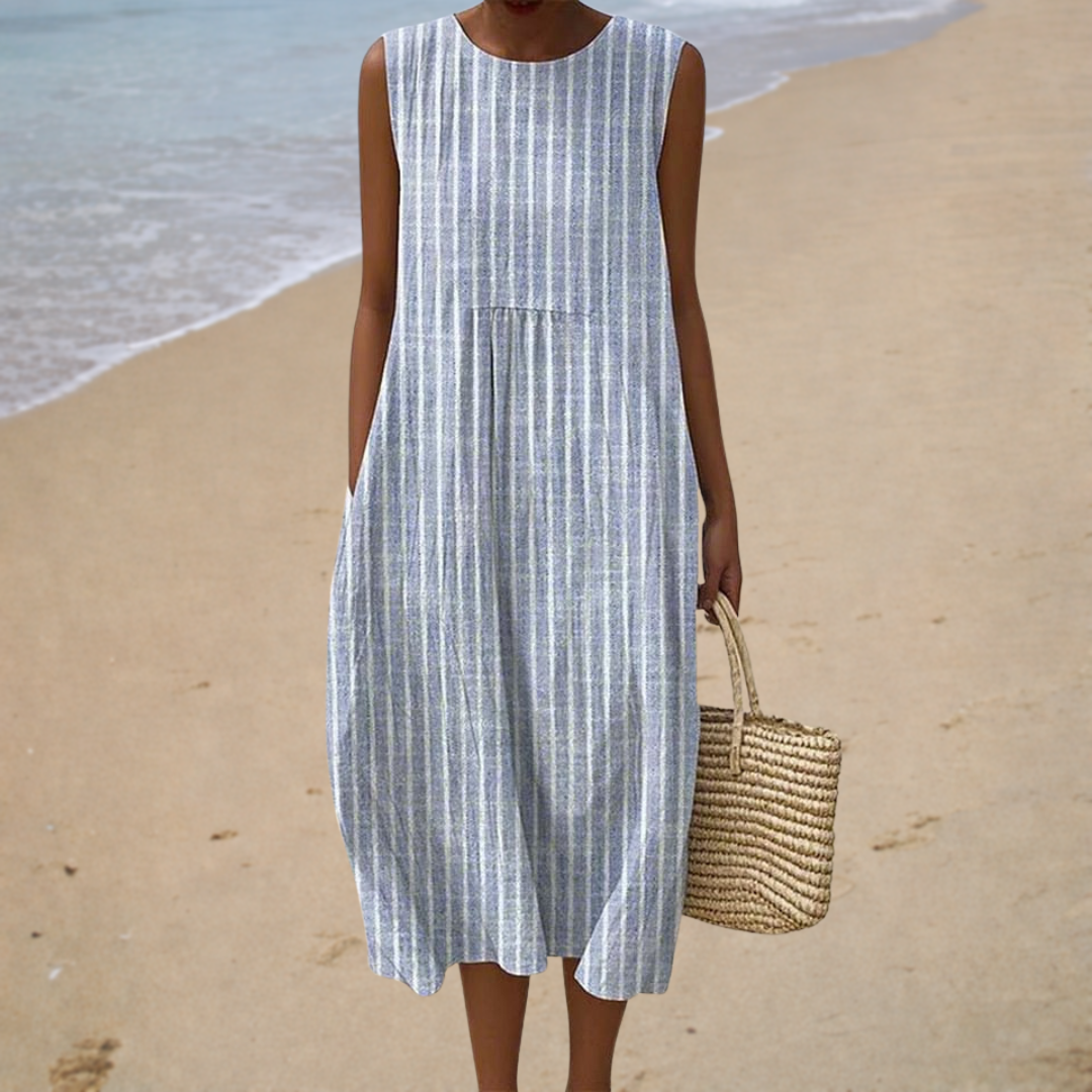 A woman wearing a sleeveless patterned summer dress with a loose, airy drape.