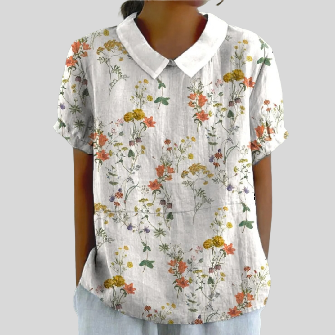 A woman wearing a delicate blossom-print top with an elegant collar, paired with a flowing skirt.