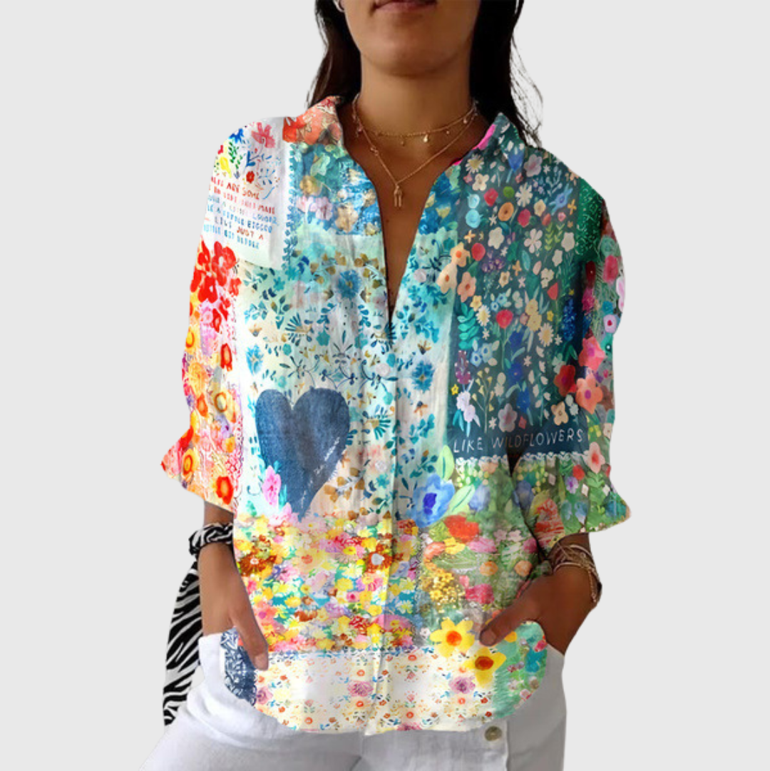 A woman smiling in a bright floral printed blouse, worn loose with pants