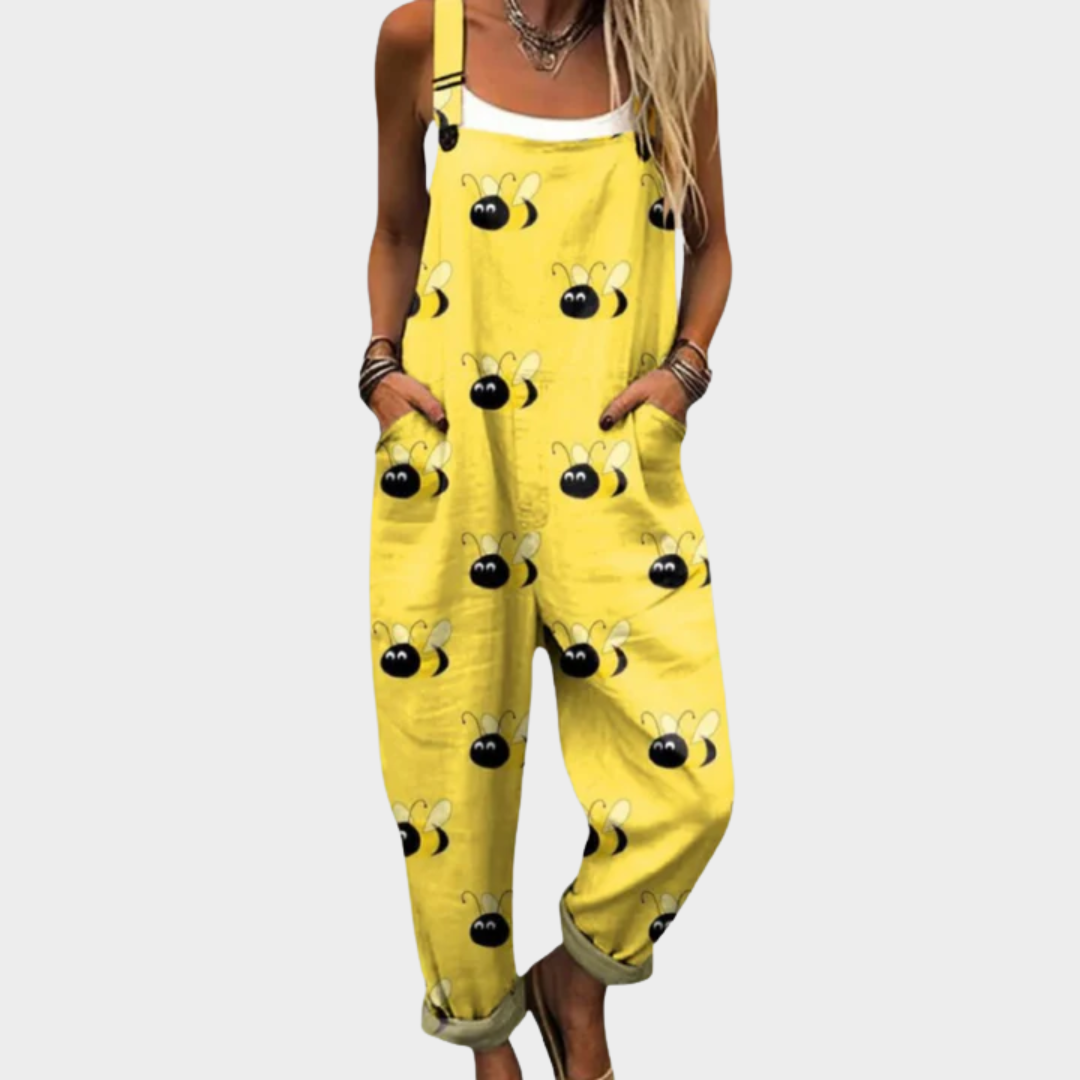 A woman smiling in bright yellow bee-print overalls with a relaxed fit and adjustable straps.