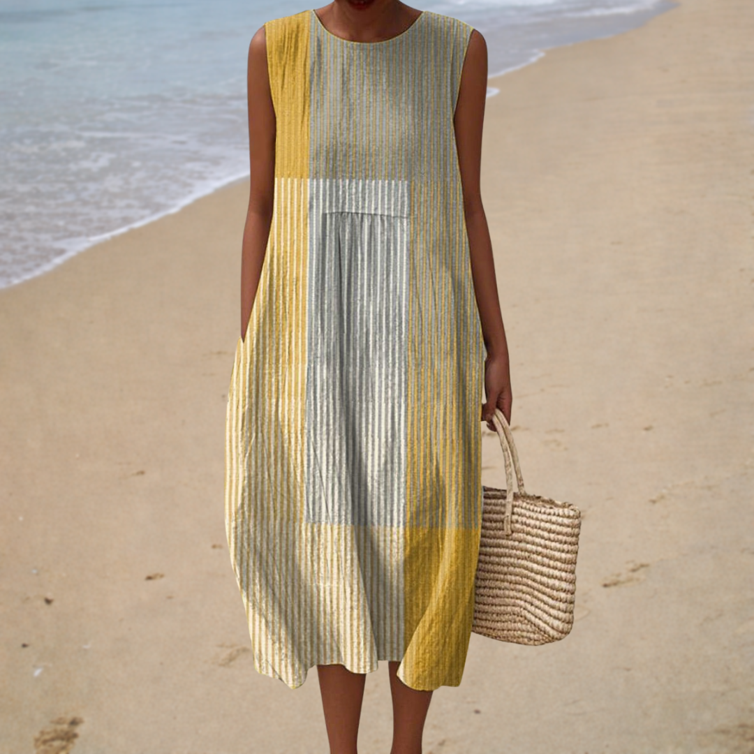 A woman wearing a sleeveless printed summer dress with a soft, loose drape.