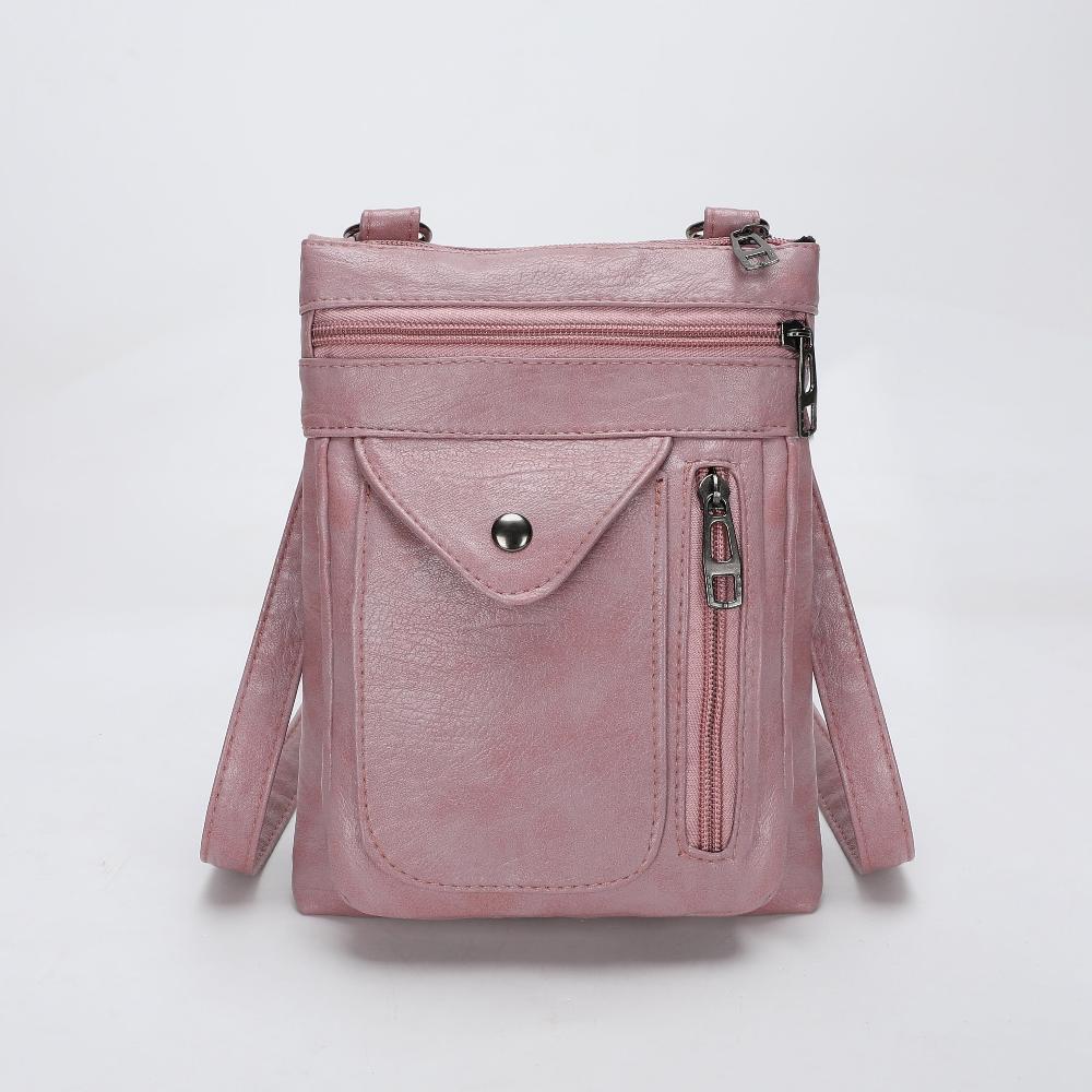 A woman wearing a compact vintage crossbody bag across her body while walking through town.