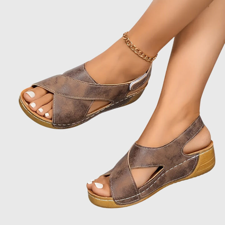 A woman wearing navy cross-strap sandals with a cushioned insole and secure heel fastening.