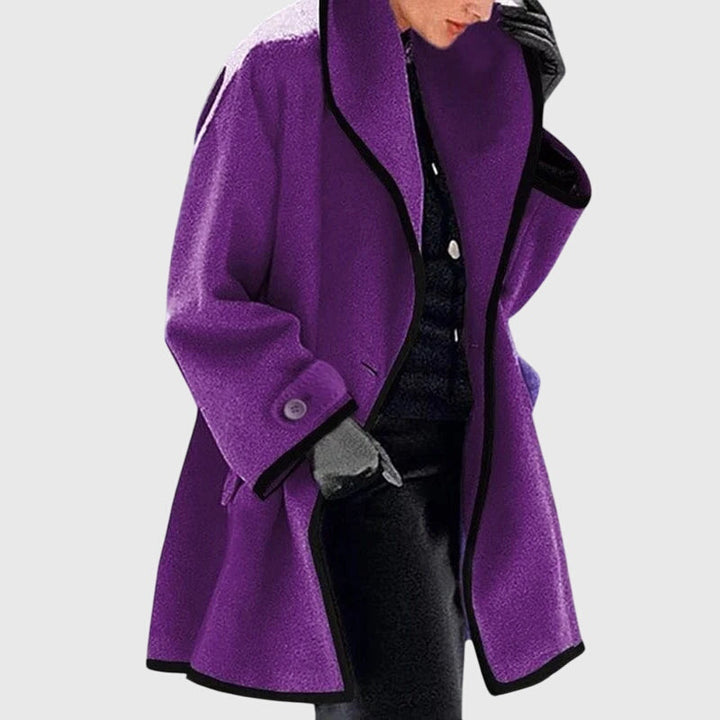 A woman wearing a blue swing-cut jacket with a black contrast trim