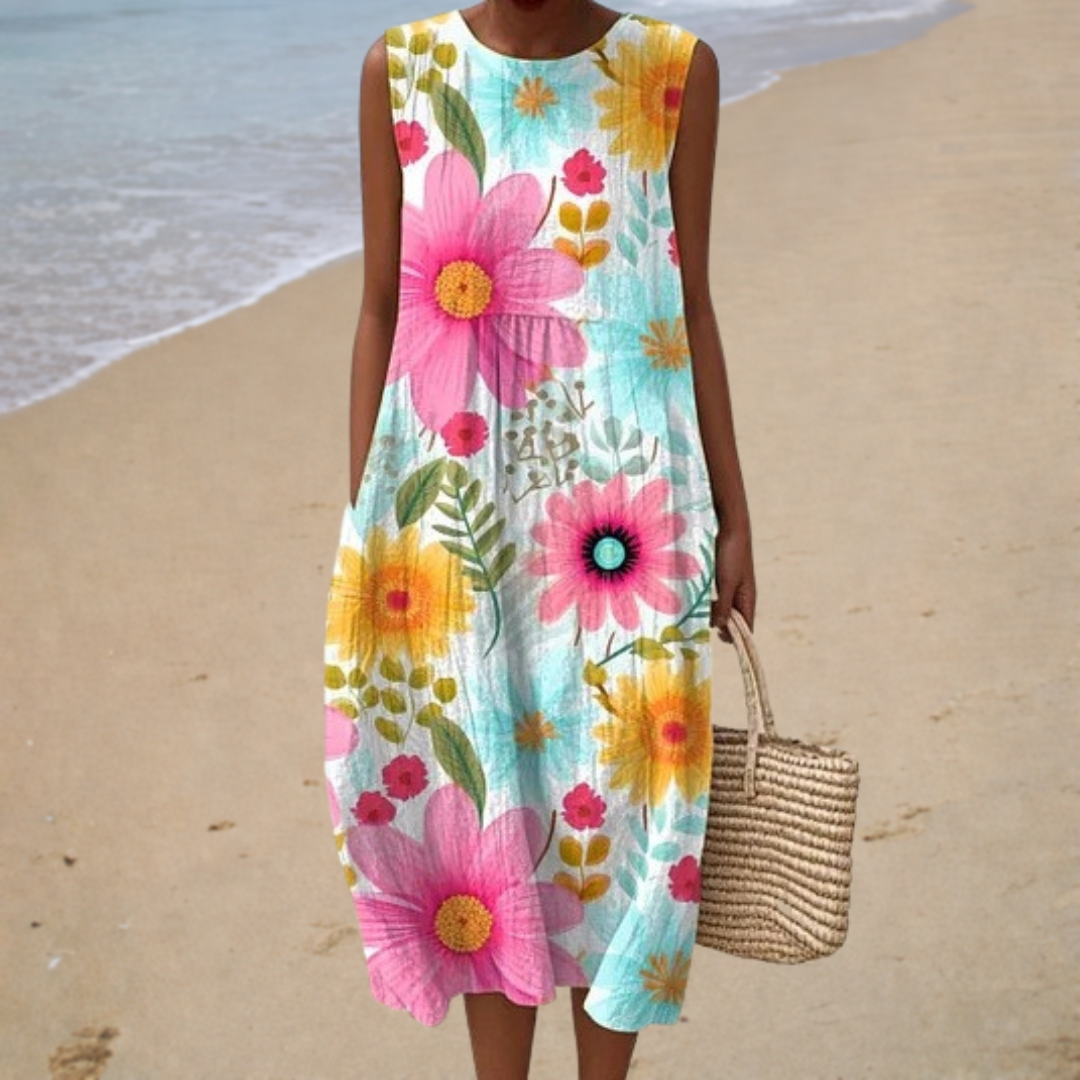 A woman wearing a light sleeveless printed summer dress, relaxed and elegant in the summer sun.