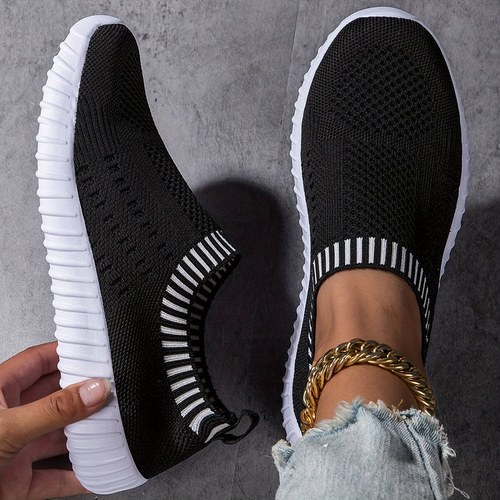 A woman slipping on ultralight sock-style sneakers that hug the foot.