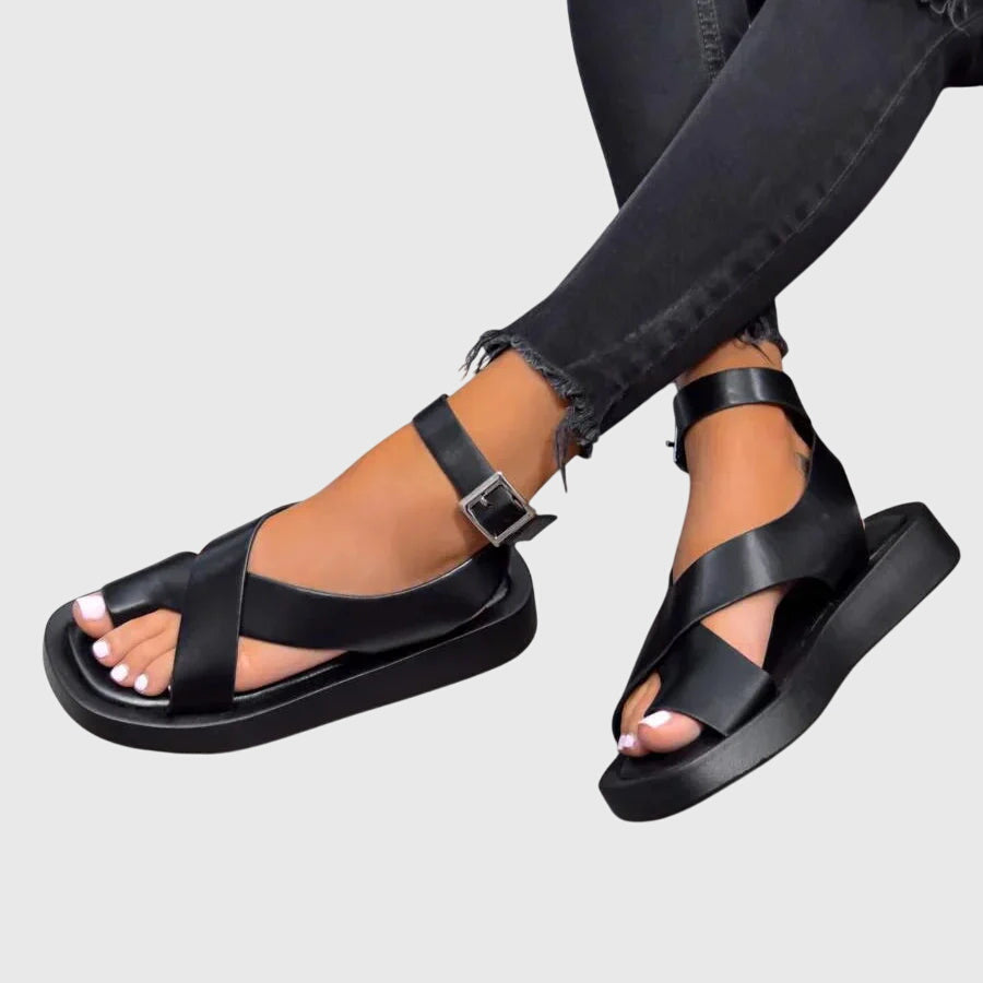 A woman in black chunky platform sandals with an ankle strap, standing confidently, feet cushioned and supported.
