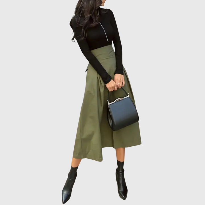 A woman wearing a flared green midi skirt with a belt detail at the waist.
