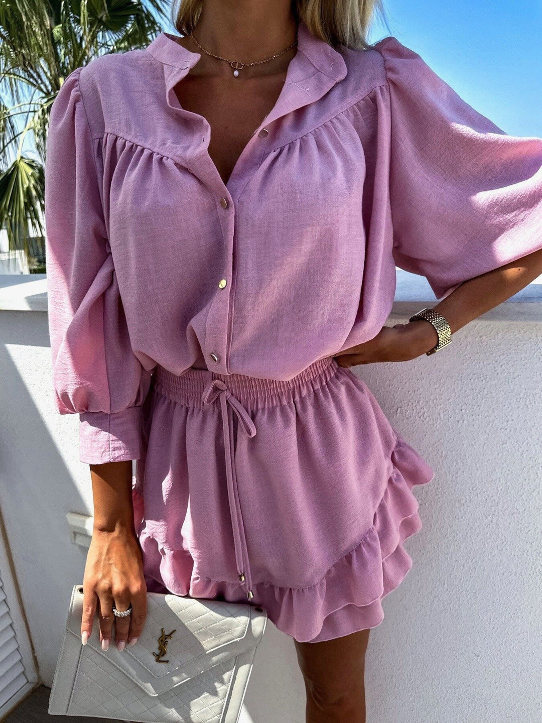 A woman wearing a white buttoned top with ruffled shorts
