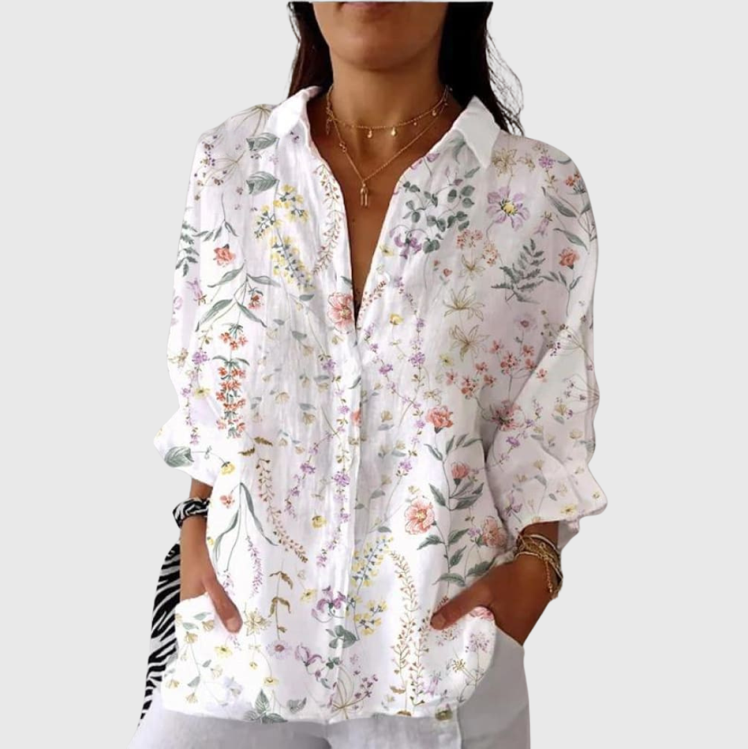 A woman in a bright floral blouse worn loose, smiling in daylight