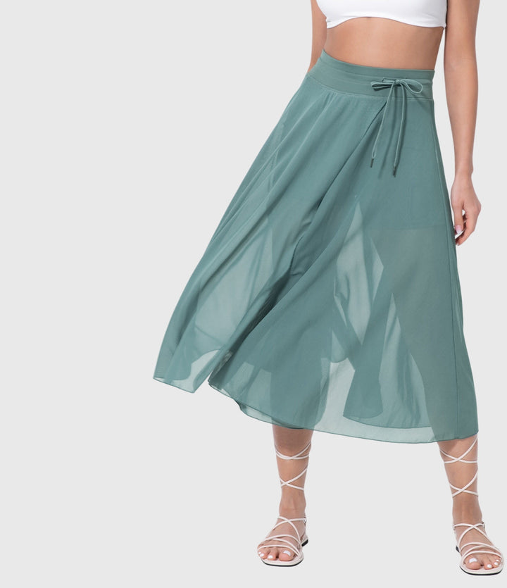 A woman in an elegant high-waisted flowing skirt, styled for a versatile day-to-evening look.