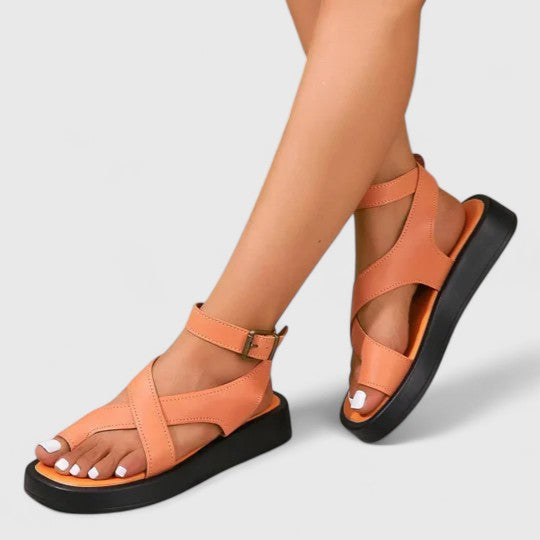 A woman walking comfortably in beige cushioned cross-strap sandals with an adjustable ankle buckle.