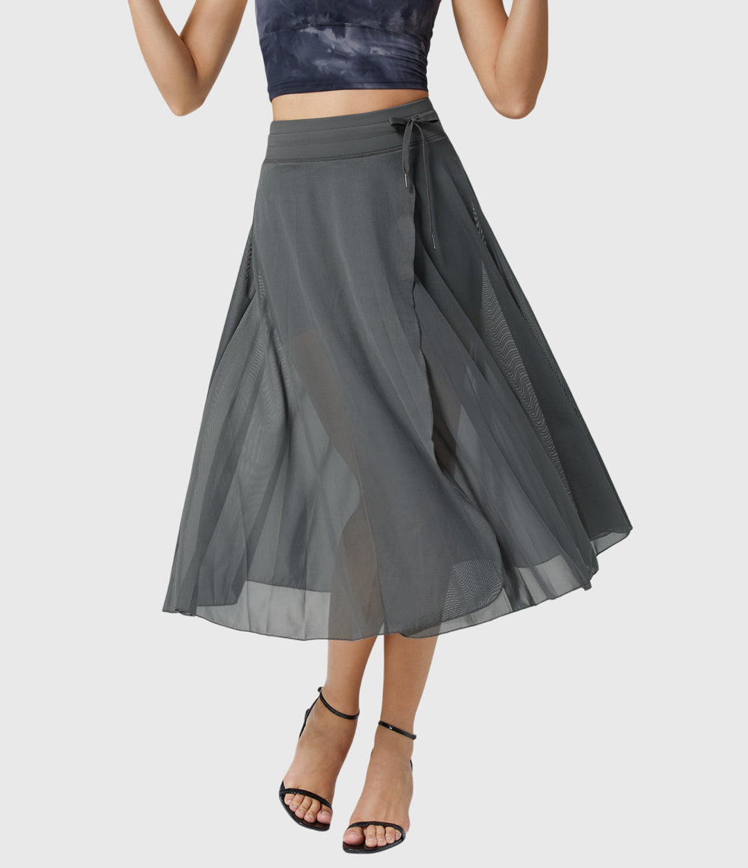 A woman in an elegant high-waisted flowing skirt, styled for a versatile day-to-evening look.