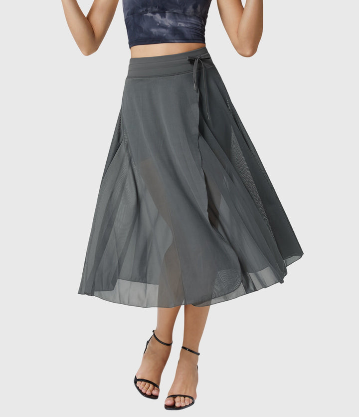 A woman in an elegant high-waisted flowing skirt, styled for a versatile day-to-evening look.