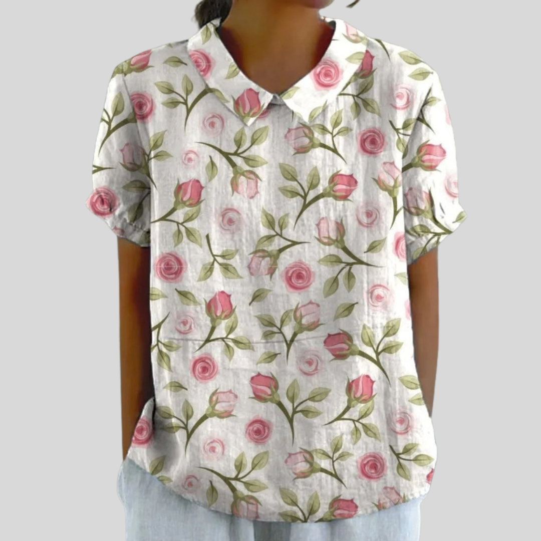 A woman wearing a flowing floral top with a polo collar, looking feminine and well dressed.