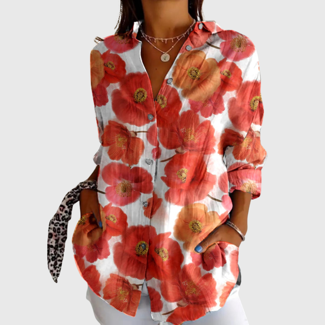 A woman wearing a vibrant floral printed blouse, relaxed and smiling