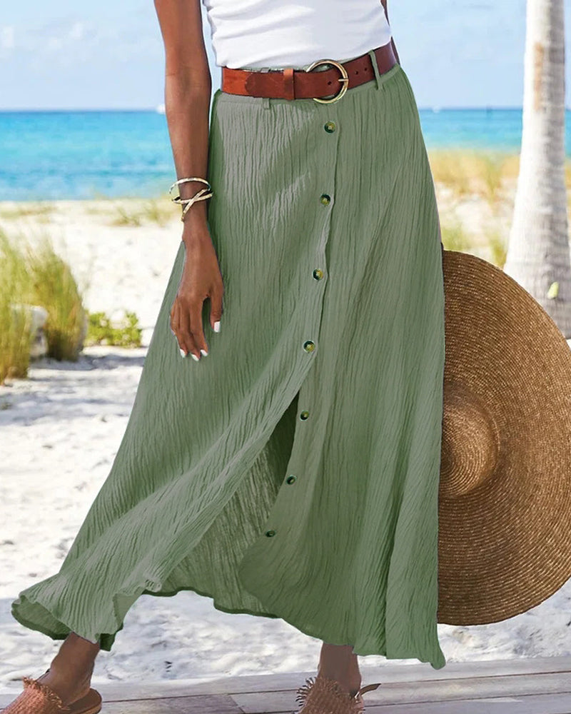 Woman wearing a flowing high-waisted button skirt with a tucked-in top, walking outdoors.