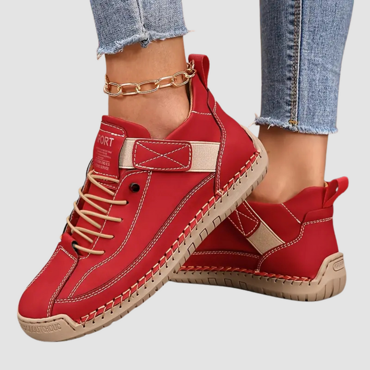 A woman wearing white lace-up orthopaedic sneakers with an adjustable strap.
