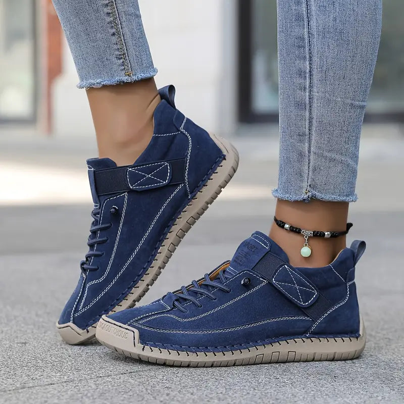 A woman wearing white lace-up orthopaedic sneakers with an adjustable strap.